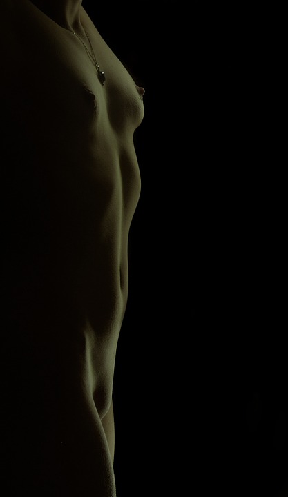 Naken kvinna snett i profil där bröst och underliv syns